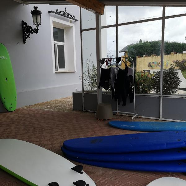 Terraza cubierta de las instalaciones con tablas y ropa para la práctica del surf